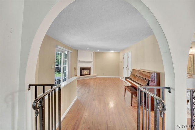 61 Caesar Blvd, Amherst, NY 14221 - living area with light wood-type flooring, a large fireplace, baseboards, a textured ceiling, and arched walkways