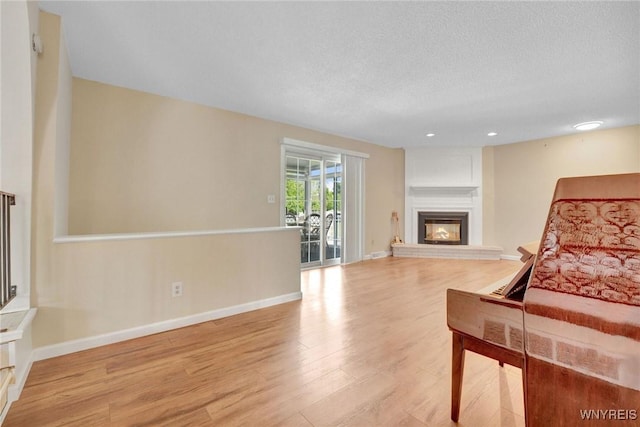 61 Caesar Blvd, Amherst, NY 14221 - living room featuring wood finished floors, a large fireplace, baseboards, a textured ceiling, and recessed lighting