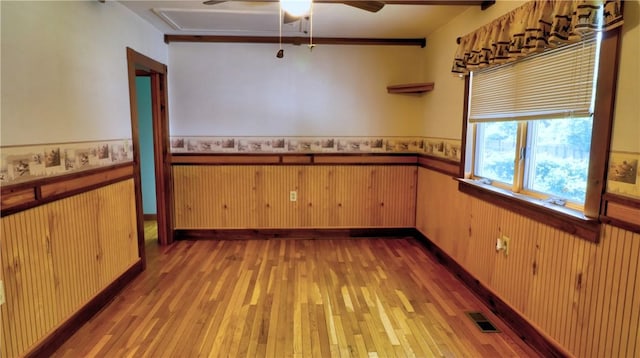 6251 Willard St, Aurelius, NY 13034 - unfurnished dining area featuring a wainscoted wall, light wood-style floors, and ceiling fan