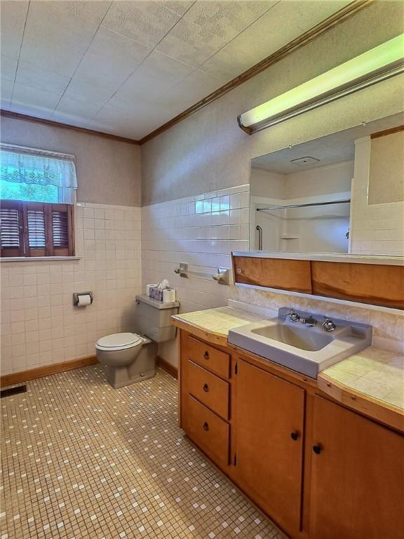 6251 Willard St, Aurelius, NY 13034 - bathroom featuring tile walls, toilet, vanity, and ornamental molding