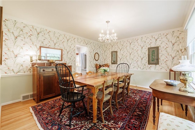 307 Allens Creek Rd, Brighton, NY 14618 - dining area featuring wallpapered walls, crown molding, light wood-style flooring, a chandelier, and wainscoting