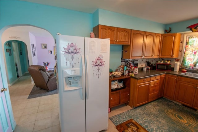 249 Glasgow St, Galen, NY 14433 - kitchen with white fridge with ice dispenser, black microwave, brown cabinetry, and arched walkways