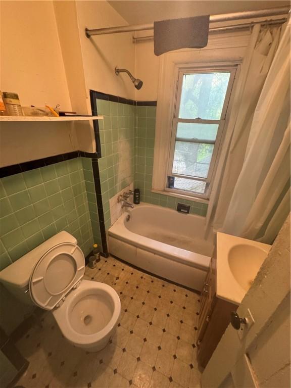 94 Lorimer St, Rochester, NY 14608 - bathroom featuring tile walls, toilet, shower / tub combo with curtain, wainscoting, and vanity