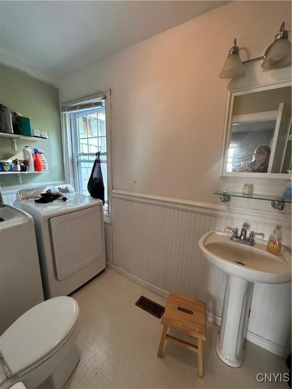 28 Payne St, Hamilton, NY 13346 - bathroom featuring washing machine and clothes dryer, wainscoting, toilet, and a sink