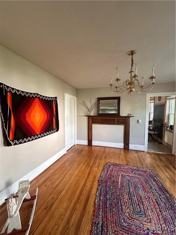 28 Payne St, Hamilton, NY 13346 - unfurnished living room featuring a chandelier, wood finished floors, and baseboards