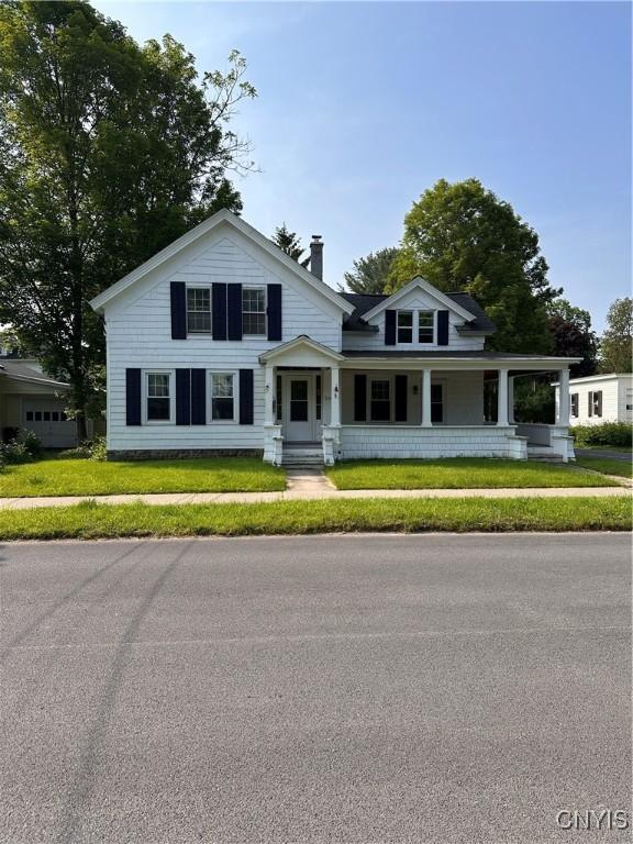 28 Payne St, Hamilton, NY 13346 - view of front of house with a chimney, covered porch, and a front lawn