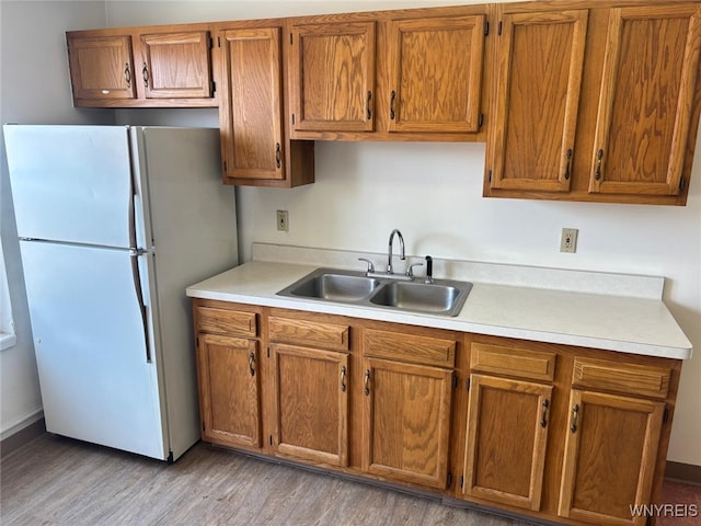 639 17th St, Niagara Falls, NY 14301 - kitchen with freestanding refrigerator, a sink, light wood-type flooring, light countertops, and brown cabinetry