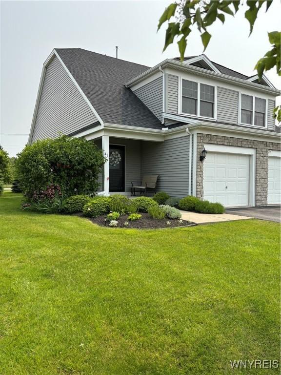 41 Brocton Dr, Lancaster, NY 14086 - view of front of property featuring a garage, a front yard, stone siding, and a shingled roof