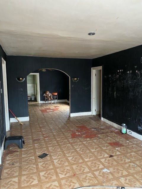 130 E Delavan Ave Unit N, Buffalo, NY 14208 - spare room featuring arched walkways, wood walls, baseboards, and light flooring