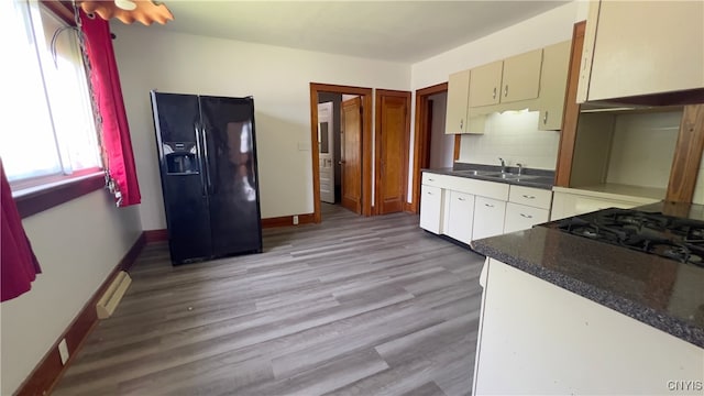 1324 Butternut St, Utica, NY 13502 - kitchen featuring black fridge with ice dispenser, a sink, light wood-style flooring, dark countertops, and baseboards