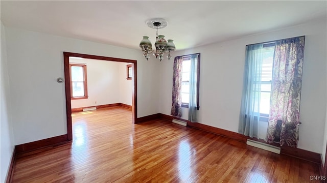 1324 Butternut St, Utica, NY 13502 - empty room featuring a baseboard radiator, a chandelier, wood finished floors, a baseboard heating unit, and baseboards