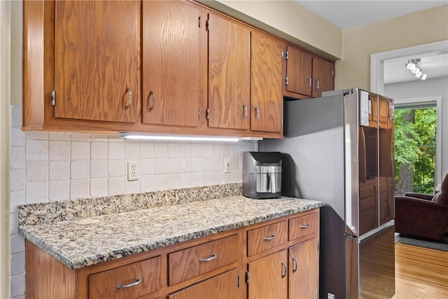 529 Backus Rd, Webster, NY 14580 - kitchen with freestanding refrigerator, decorative backsplash, brown cabinets, light wood-type flooring, and light stone counters