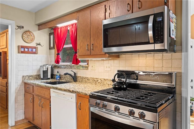 529 Backus Rd, Webster, NY 14580 - kitchen featuring stainless steel appliances, a sink, brown cabinets, light stone counters, and tile walls