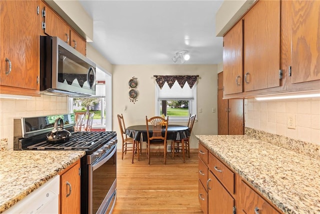 529 Backus Rd, Webster, NY 14580 - kitchen with stainless steel appliances, light wood-style flooring, brown cabinetry, and decorative backsplash
