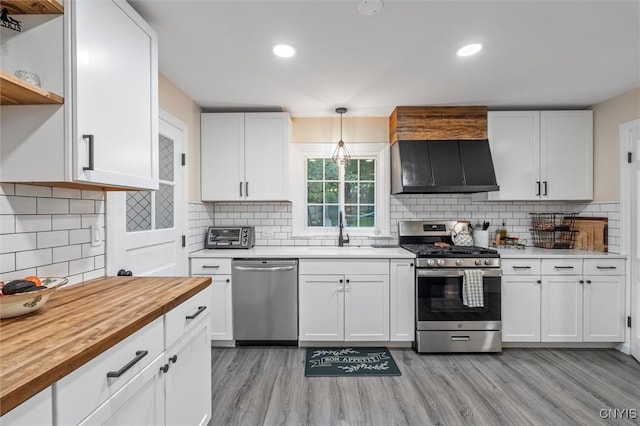 101 Doll Pkwy, Syracuse, NY 13214 - kitchen with stainless steel appliances, butcher block countertops, a sink, ventilation hood, and white cabinetry