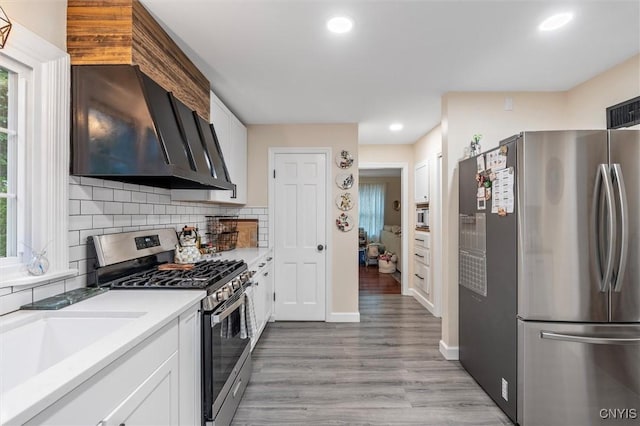 101 Doll Pkwy, Syracuse, NY 13214 - kitchen featuring appliances with stainless steel finishes, white cabinetry, backsplash, wall chimney range hood, and recessed lighting