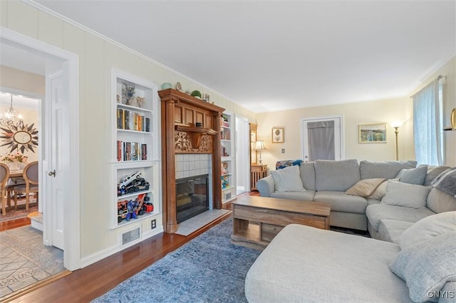 101 Doll Pkwy, Syracuse, NY 13214 - living room with wood finished floors, built in shelves, a tiled fireplace, ornamental molding, and a chandelier