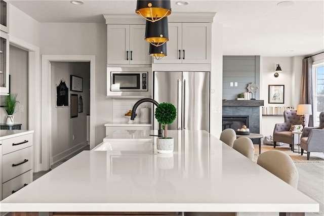 108 Chase Meadow Trl, Mendon, NY 14472 - kitchen featuring appliances with stainless steel finishes, a kitchen island, light countertops, a glass covered fireplace, and recessed lighting