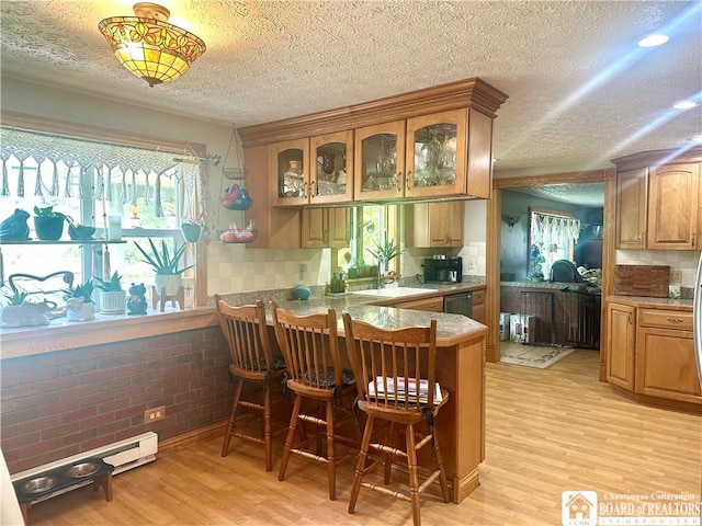 9983 Deer Creek Rd, Genesee, NY 14770 - kitchen with healthy amount of natural light, a breakfast bar, light wood-style flooring, a textured ceiling, and glass insert cabinets