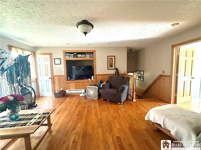 9983 Deer Creek Rd, Genesee, NY 14770 - living area with wainscoting, a baseboard radiator, a textured ceiling, wood finished floors, and wooden walls