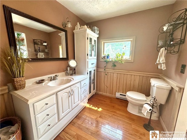 9983 Deer Creek Rd, Genesee, NY 14770 - bathroom with hardwood / wood-style floors, toilet, a wainscoted wall, vanity, and a baseboard heating unit