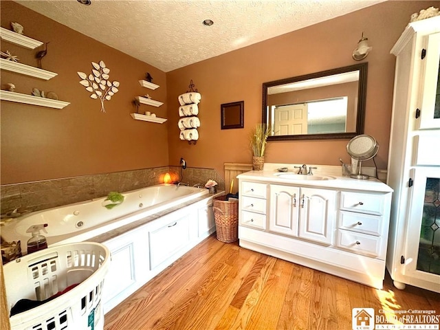 9983 Deer Creek Rd, Genesee, NY 14770 - full bath with a textured ceiling, vanity, a tub with jets, and wood finished floors