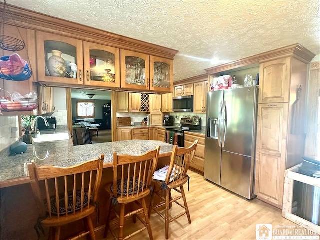 9983 Deer Creek Rd, Genesee, NY 14770 - kitchen with stainless steel appliances, a sink, glass insert cabinets, a peninsula, and light wood finished floors