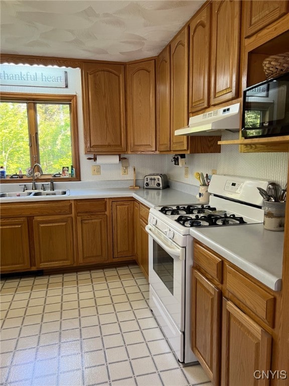 381 French Rd, Morehouse, NY 13324 - kitchen with white gas stove, under cabinet range hood, a sink, black microwave, and light countertops