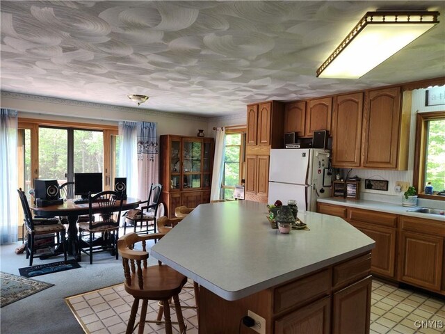 381 French Rd, Morehouse, NY 13324 - kitchen featuring freestanding refrigerator, brown cabinets, light countertops, a kitchen breakfast bar, and a kitchen island