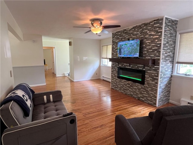 793 Helendale Rd, Irondequoit, NY 14609 - living room featuring wood finished floors, baseboard heating, a ceiling fan, a large fireplace, and baseboards