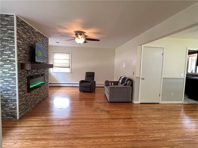 793 Helendale Rd, Irondequoit, NY 14609 - living room featuring a baseboard heating unit, a ceiling fan, wood finished floors, a large fireplace, and healthy amount of natural light