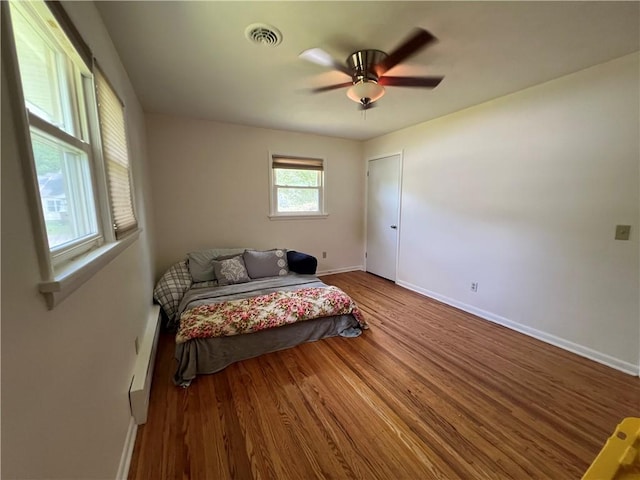 793 Helendale Rd, Irondequoit, NY 14609 - bedroom with baseboards, wood finished floors, a baseboard heating unit, and a ceiling fan