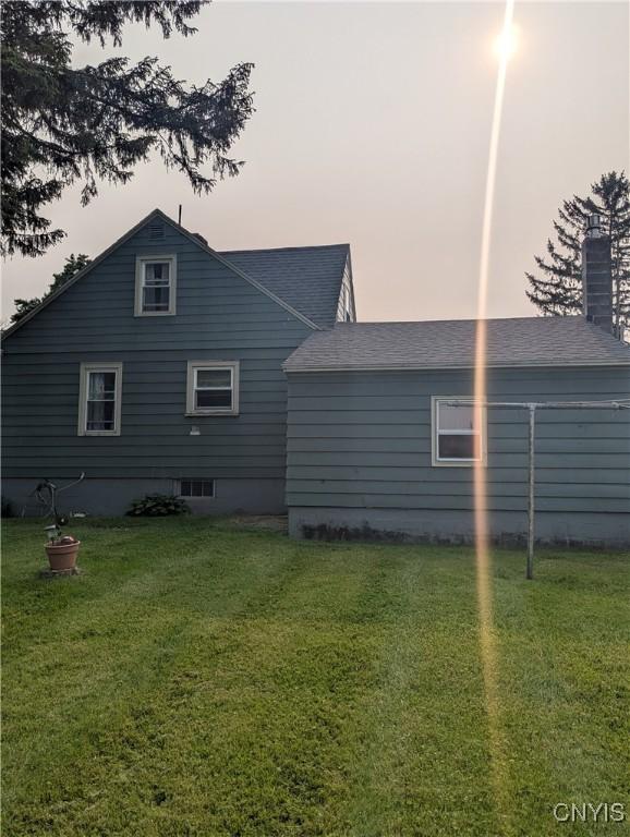 311 Raphael Ave, Salina, NY 13211 - back of property at dusk featuring a lawn, a shingled roof, and a chimney