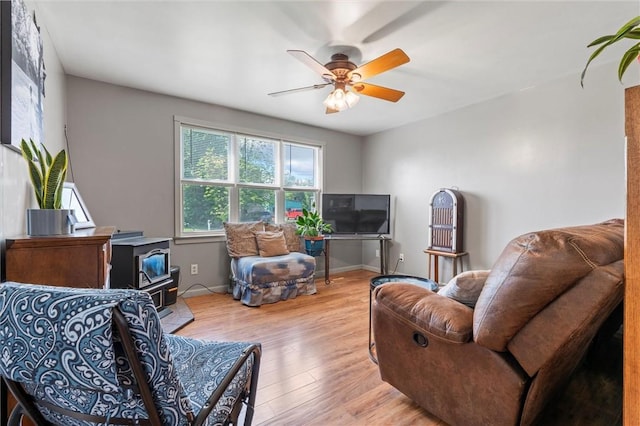 13385 Seneca St, Savannah, NY 13146 - living area featuring a wood stove, wood finished floors, a ceiling fan, and baseboards