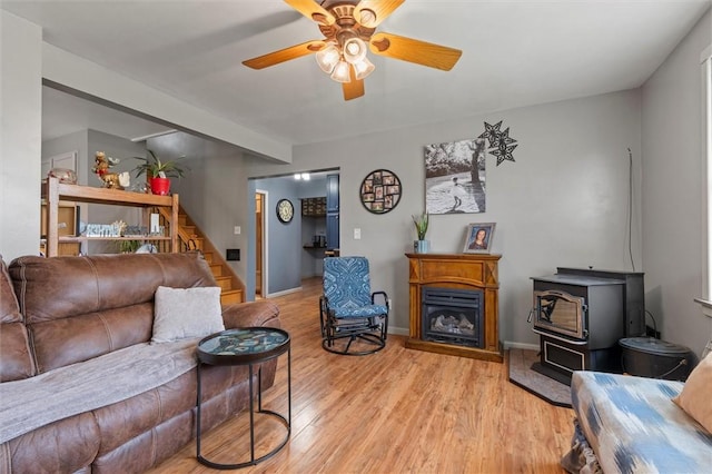 13385 Seneca St, Savannah, NY 13146 - living area with stairway, ceiling fan, light wood finished floors, a wood stove, and baseboards