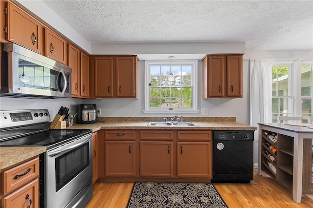 11 Shadow Ln, Gates, NY 14606 - kitchen with stainless steel appliances, light wood-type flooring, a sink, a textured ceiling, and brown cabinetry