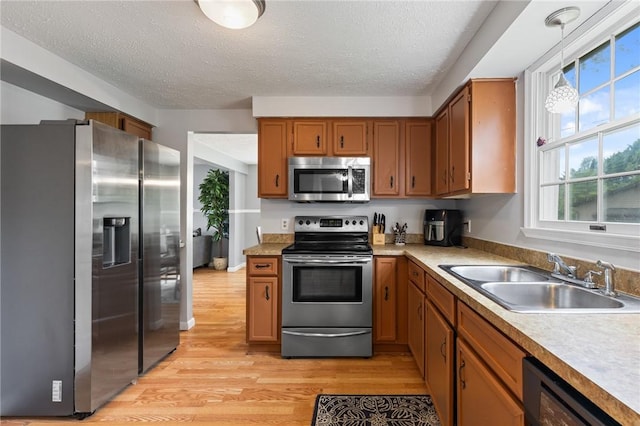 11 Shadow Ln, Gates, NY 14606 - kitchen with stainless steel appliances, a sink, light wood-style floors, brown cabinets, and a textured ceiling
