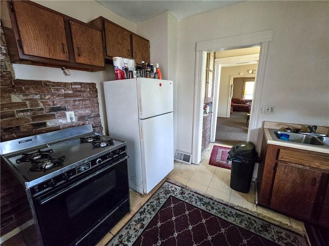 40 Grover St, Rochester, NY 14611 - kitchen featuring black gas stove, freestanding refrigerator, a sink, light countertops, and brown cabinetry