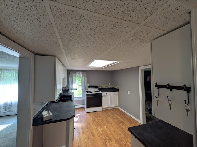 135 Hedgehog Ln, Bradford Town, PA 16701 - kitchen featuring gas range gas stove, a paneled ceiling, dark countertops, light wood-type flooring, and white cabinets
