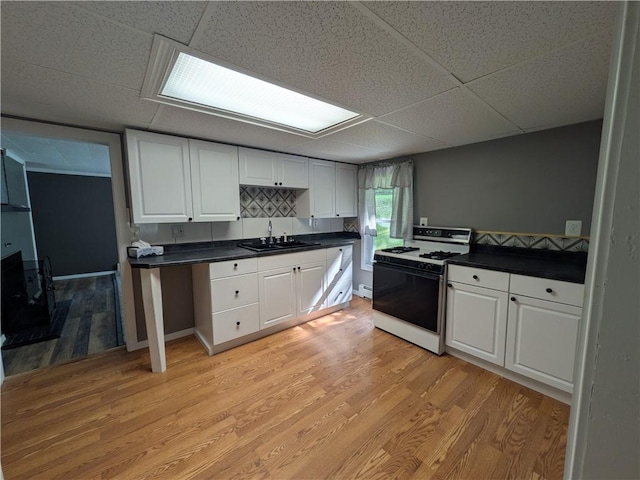 135 Hedgehog Ln, Bradford Town, PA 16701 - kitchen with range with gas stovetop, a sink, a paneled ceiling, dark countertops, and white cabinetry