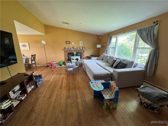 57 Brookdale Dr, Amherst, NY 14221 - living room featuring vaulted ceiling, a fireplace, hardwood / wood-style floors, and a baseboard heating unit