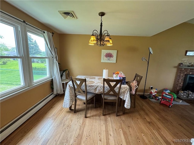 57 Brookdale Dr, Amherst, NY 14221 - dining space with a baseboard heating unit, light wood-style flooring, a chandelier, a brick fireplace, and baseboards