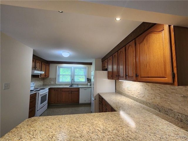 70 W Elizabeth St, Skaneateles, NY 13152 - kitchen featuring white appliances, under cabinet range hood, backsplash, brown cabinets, and light stone countertops