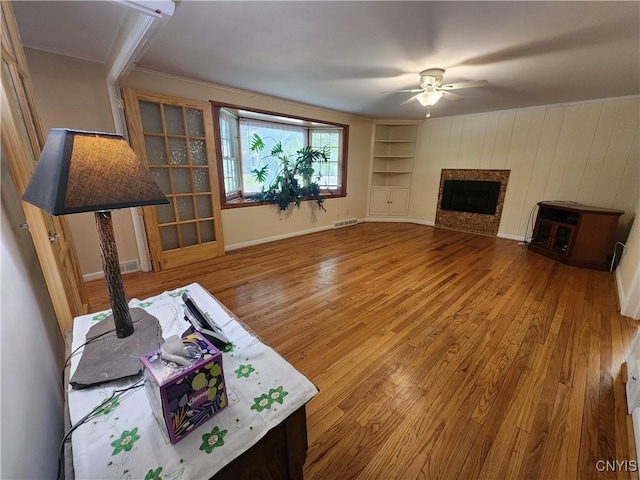 70 W Elizabeth St, Skaneateles, NY 13152 - unfurnished living room with a ceiling fan, wood finished floors, a fireplace, and built in shelves