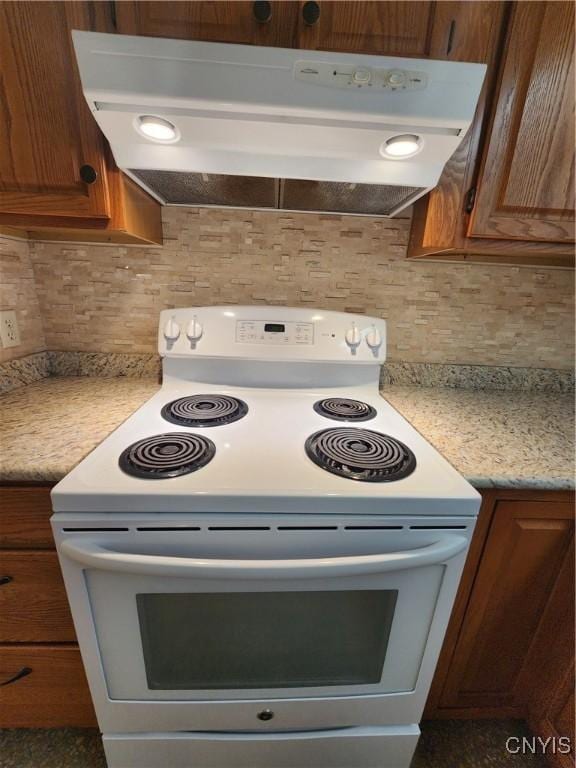 70 W Elizabeth St, Skaneateles, NY 13152 - kitchen with white range with electric stovetop, under cabinet range hood, backsplash, light countertops, and brown cabinetry