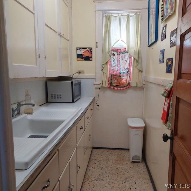 50 Gualbert Ave, Cheektowaga, NY 14211 - kitchen featuring stainless steel microwave, light countertops, white cabinets, and a sink