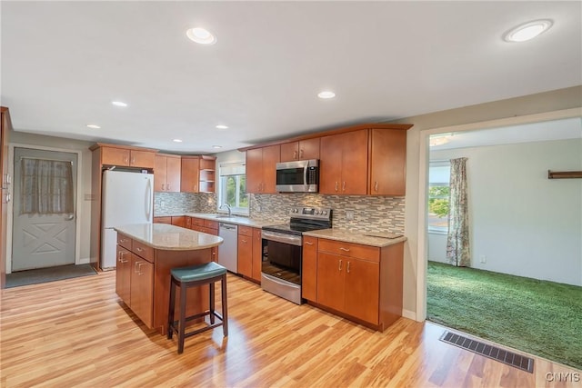 8278 Maple Rd, Clay, NY 13041 - kitchen with stainless steel appliances, a sink, light wood finished floors, open shelves, and decorative backsplash
