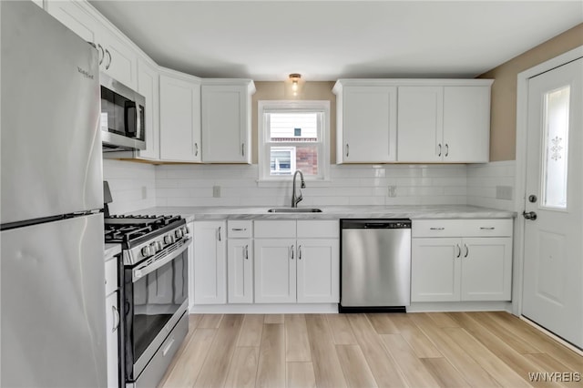 49 Central Blvd, Cheektowaga, NY 14225 - kitchen featuring stainless steel appliances, a sink, white cabinets, tasteful backsplash, and light wood-style flooring