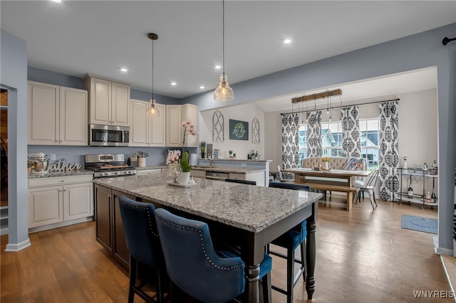123 Stonebridge Rd, Grand Island, NY 14072 - kitchen with appliances with stainless steel finishes, a center island, light stone countertops, a kitchen bar, and hanging light fixtures
