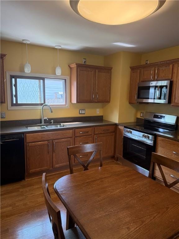 16 Cobbles E, Elmira, NY 14905 - kitchen with stainless steel appliances, a sink, dark countertops, dark wood-type flooring, and brown cabinets